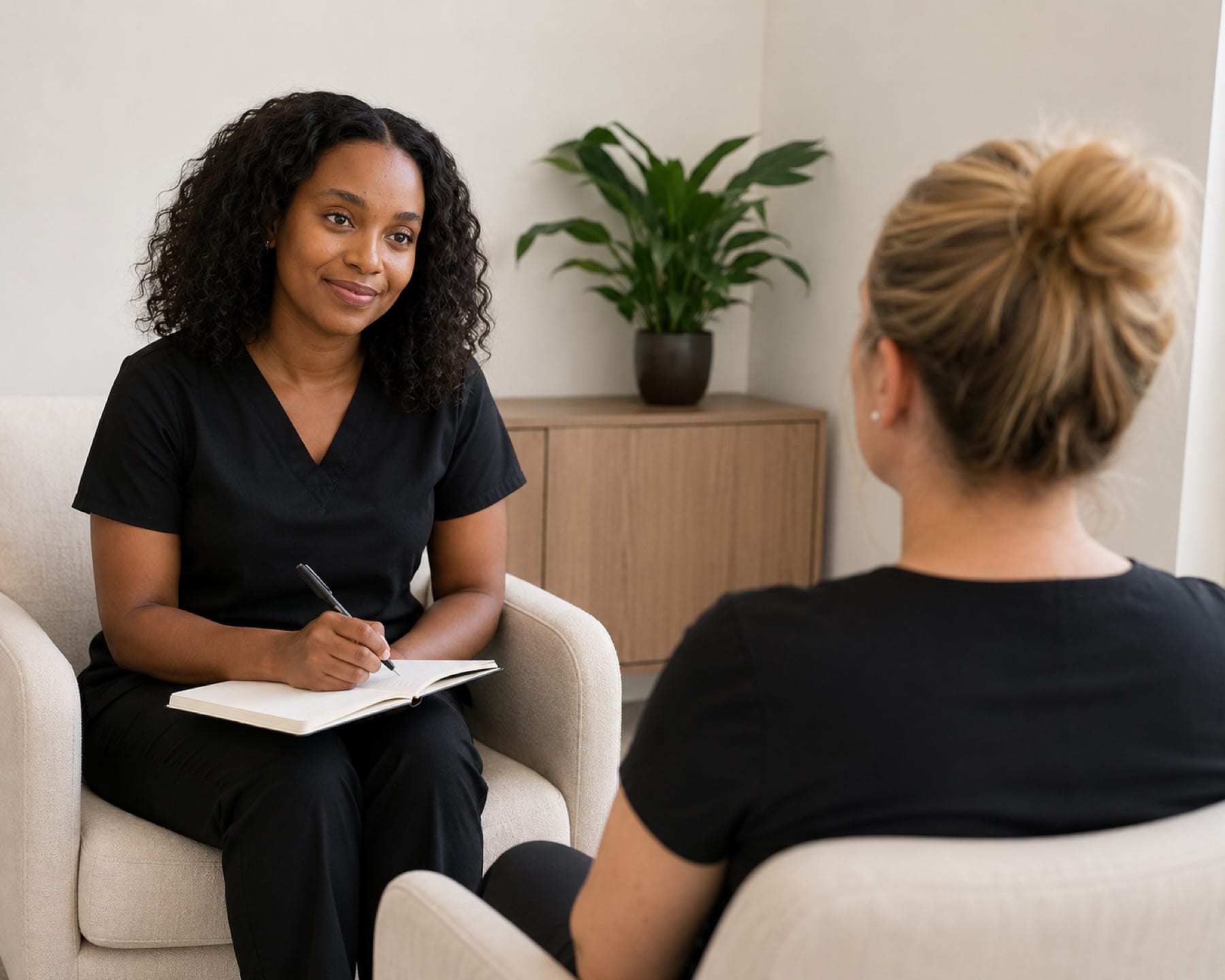 A Be Whole Care practitioner listening and taking notes during a one-to-one session.